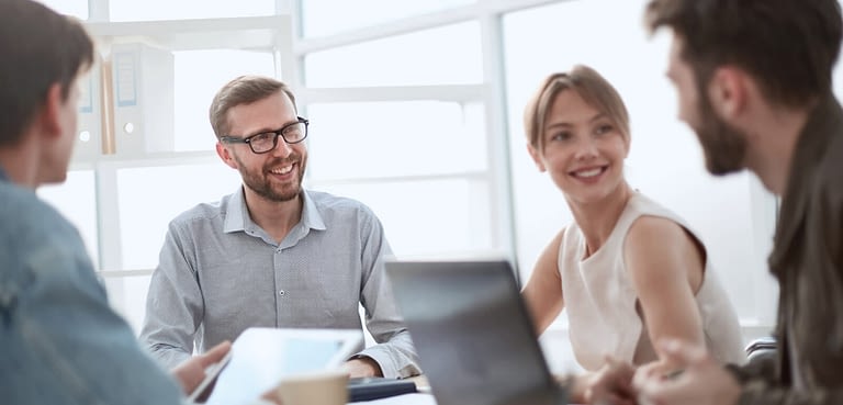 Happy business people around a desk having a meeting.
